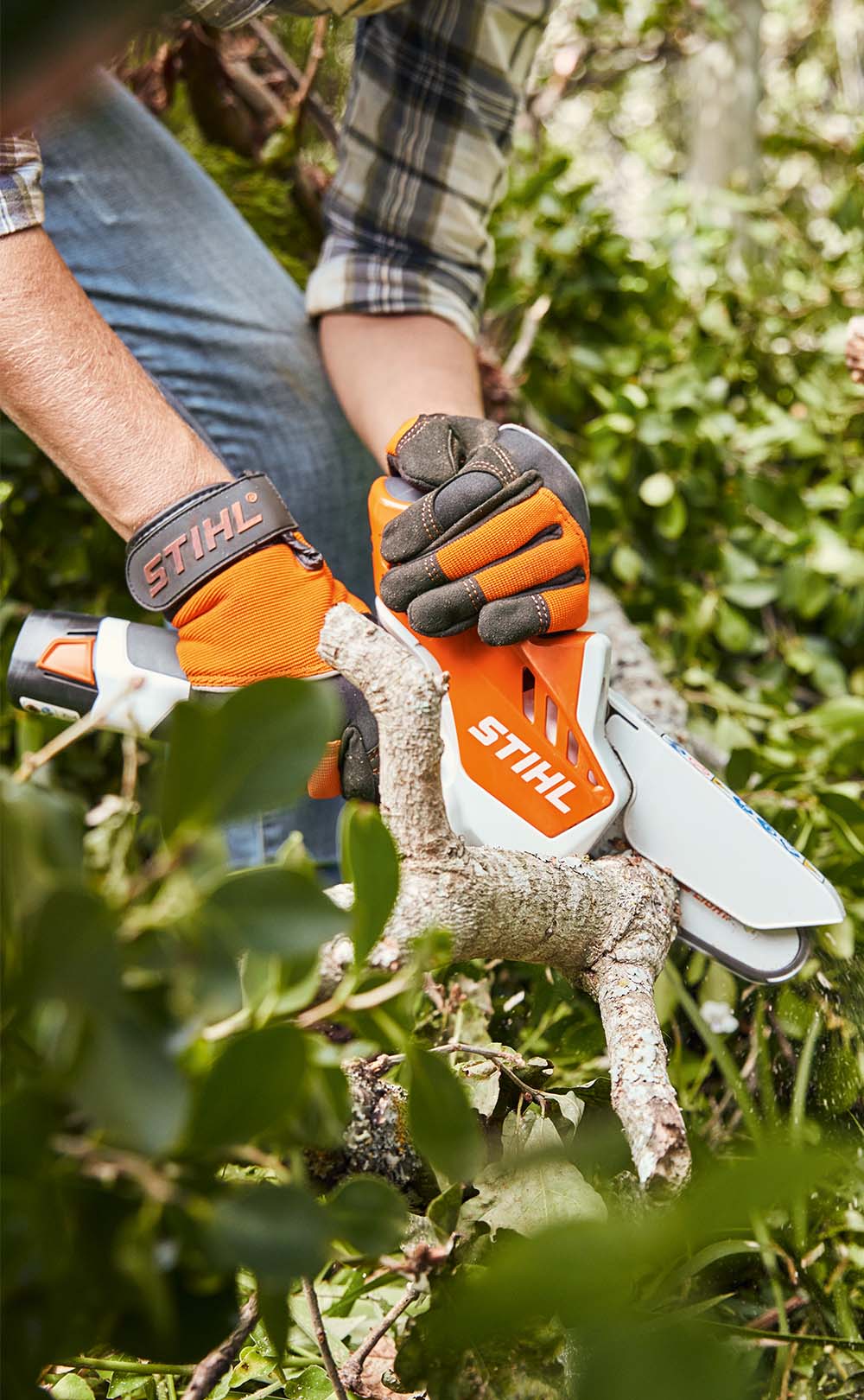 En kvinna med ansiktsskydd klipper gräs med STIHL FSA 45 batteridriven grästrimmer runt ett trappsteg framför ett hus